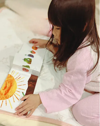 はらぺこあおむしの絵本を読む女の子